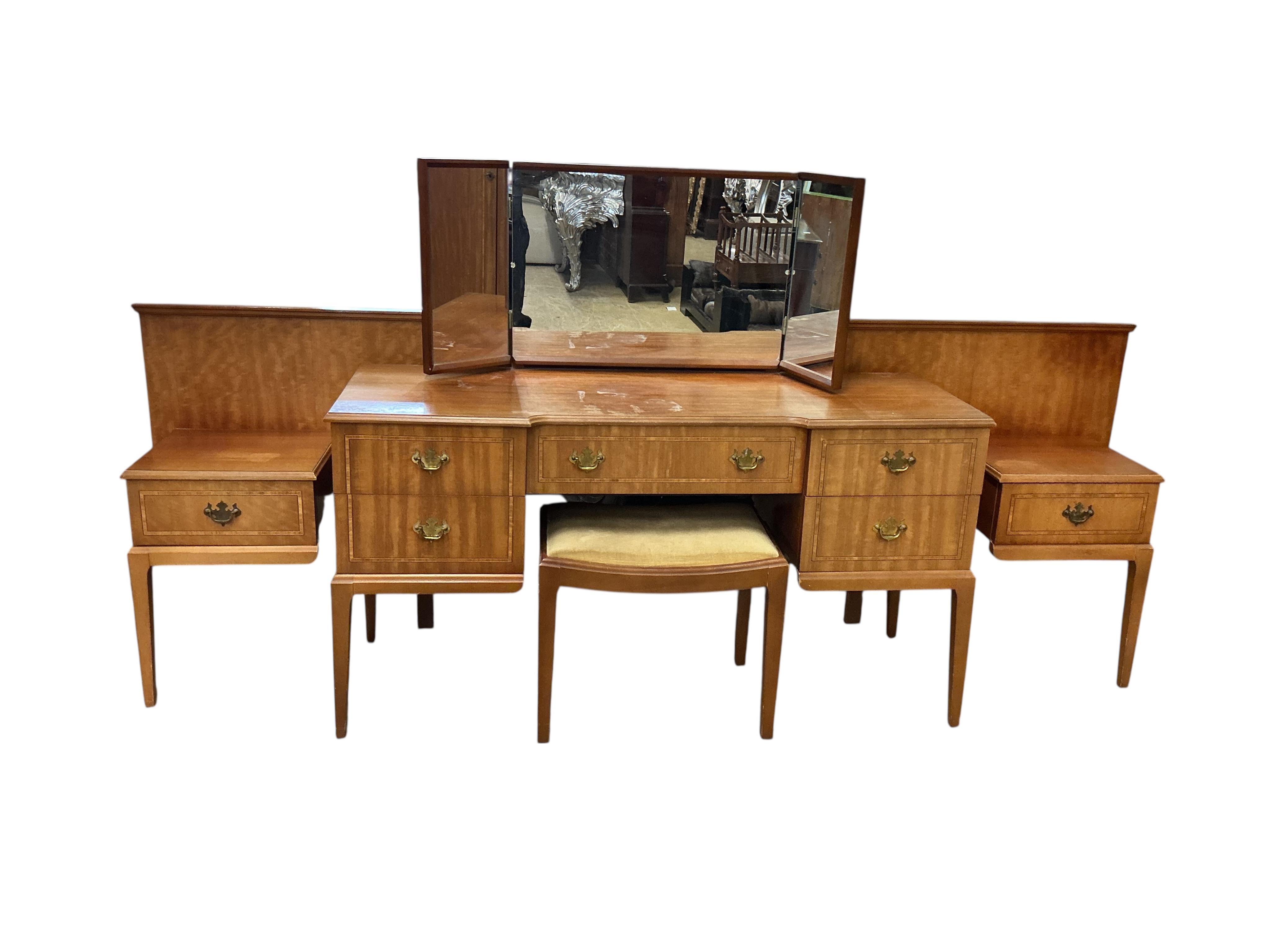 A mid century teak Beithcraft furniture bedroom suite, comprising a two door wardrobe, a kneehole dressing table with stool, headboard and a five drawer chest